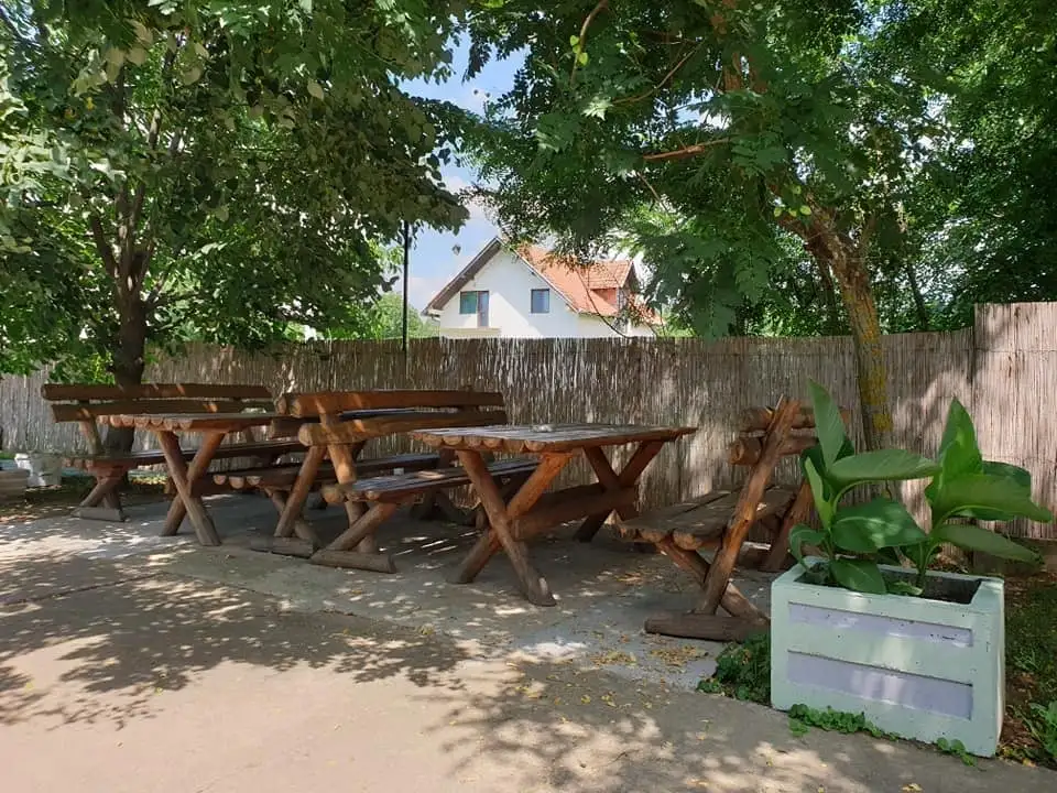 Drveni stolovi i klupe u hladu drveća u dvorištu vile